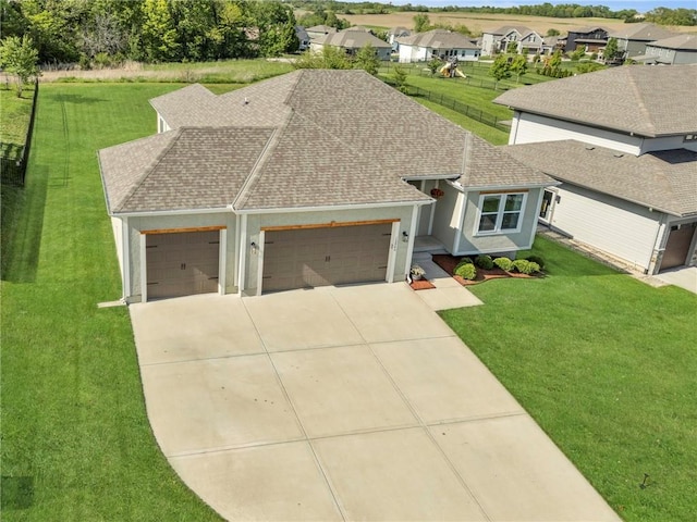 view of front of home with a garage, a shingled roof, driveway, and a front yard