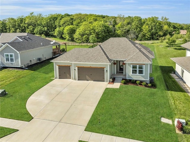ranch-style home with a garage, concrete driveway, a front lawn, a shingled roof, and stucco siding