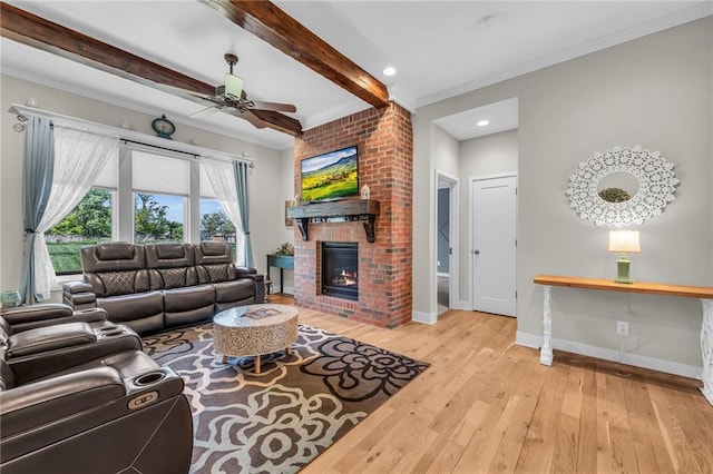 living area featuring crown molding, wood-type flooring, baseboards, a brick fireplace, and beam ceiling