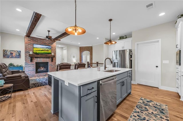 kitchen with a sink, appliances with stainless steel finishes, a ceiling fan, gray cabinets, and open floor plan