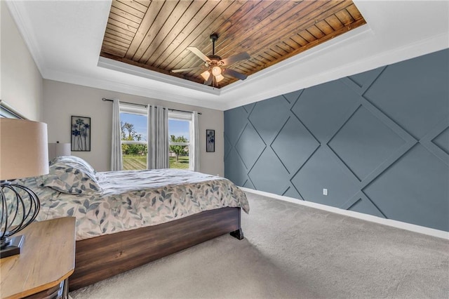 bedroom with a tray ceiling, wood ceiling, carpet flooring, a ceiling fan, and crown molding