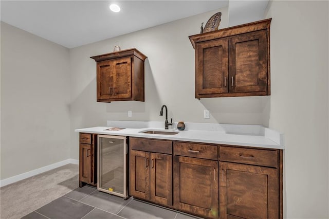 bar area featuring wine cooler, a sink, light carpet, baseboards, and light tile patterned flooring