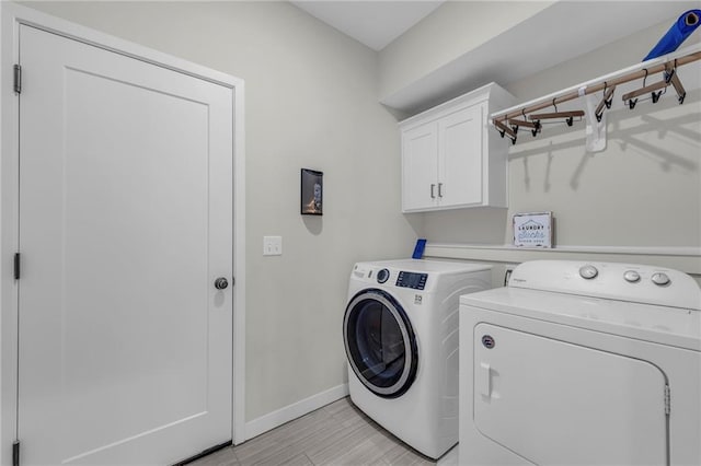 laundry room with washer and dryer, cabinet space, and baseboards