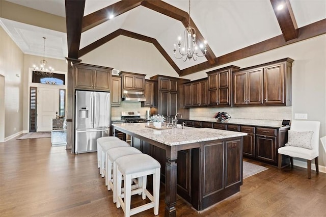 17005 Bradshaw St, Overland Park, KS 66221 - kitchen with stainless steel appliances, a chandelier, under cabinet range hood, high vaulted ceiling, and dark brown cabinetry
