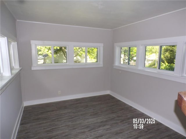spare room with baseboards and dark wood-type flooring