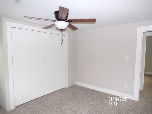 carpeted empty room featuring a ceiling fan and baseboards