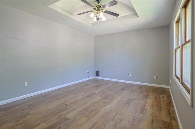 211 Carla St, Excelsior Springs, MO 64024 - spare room featuring a tray ceiling, dark wood-style floors, baseboards, and ceiling fan