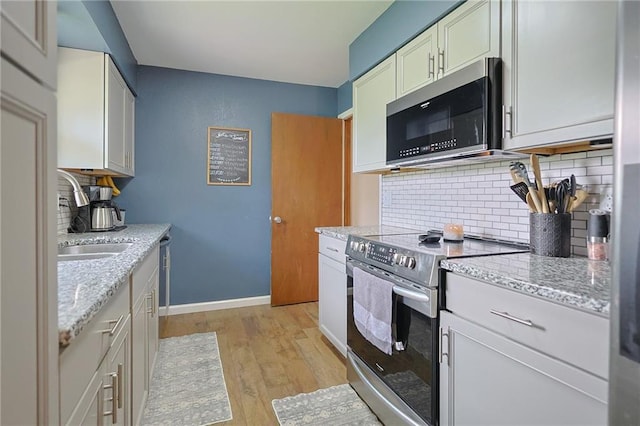 211 Carla St, Excelsior Springs, MO 64024 - kitchen with appliances with stainless steel finishes, decorative backsplash, light wood-type flooring, and a sink