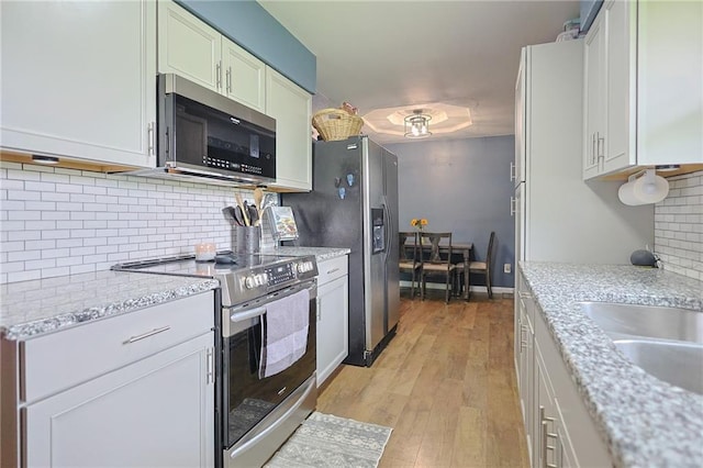 211 Carla St, Excelsior Springs, MO 64024 - kitchen featuring stainless steel appliances, backsplash, light wood-style flooring, and light stone counters