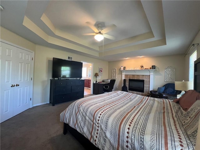 1530 Horseshoe Dr, Raymore, MO 64083 - bedroom with a tray ceiling, a tile fireplace, multiple windows, and carpet flooring