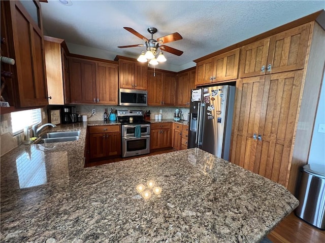1530 Horseshoe Dr, Raymore, MO 64083 - kitchen with appliances with stainless steel finishes, a sink, brown cabinets, a peninsula, and ceiling fan