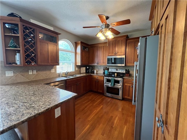 1530 Horseshoe Dr, Raymore, MO 64083 - kitchen with stainless steel appliances, dark wood-style flooring, a sink, brown cabinets, and a textured ceiling