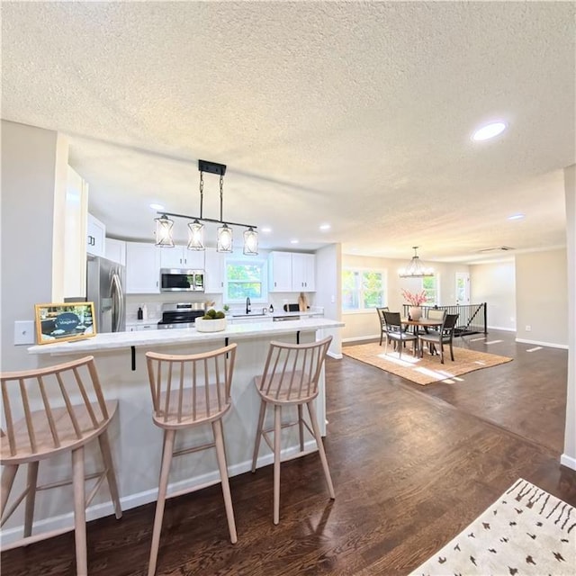 kitchen featuring stainless steel appliances, a textured ceiling, white cabinets, a sink, and light countertops