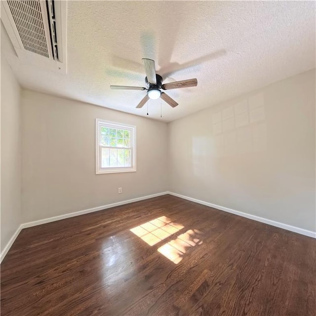 empty room featuring dark wood finished floors, baseboards, ceiling fan, and a textured ceiling