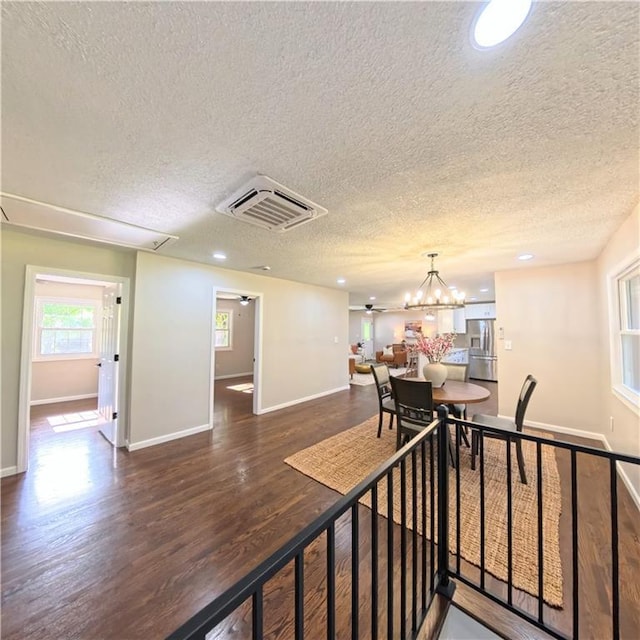 dining space featuring a textured ceiling, wood finished floors, baseboards, recessed lighting, and a chandelier