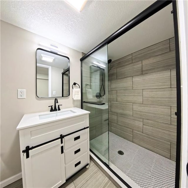full bath featuring a stall shower, a textured ceiling, and vanity