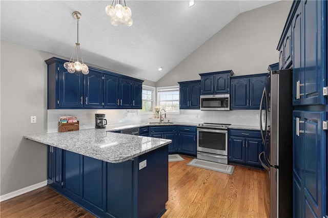 957 NW Dogwood Dr, Grain Valley, MO 64029 - kitchen featuring stainless steel appliances, a chandelier, a peninsula, a sink, and blue cabinetry