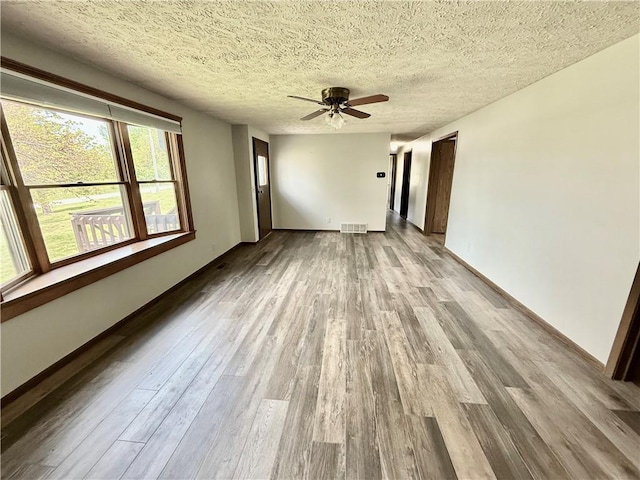 unfurnished room featuring a textured ceiling, baseboards, a ceiling fan, and wood finished floors
