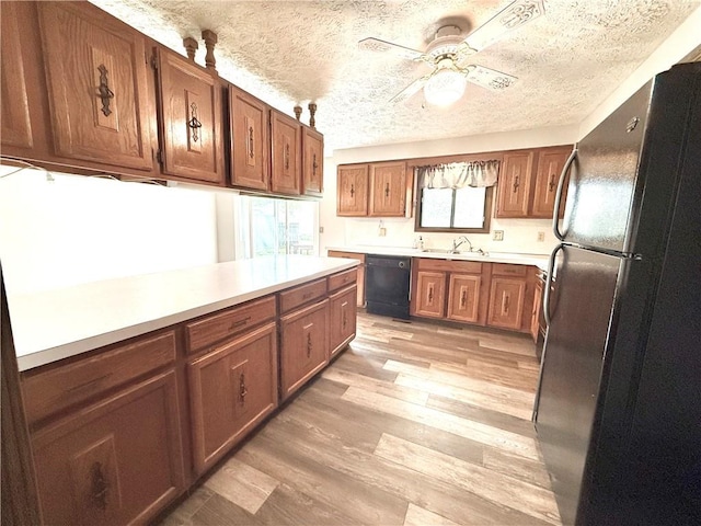 kitchen with a healthy amount of sunlight, brown cabinetry, a ceiling fan, and black appliances