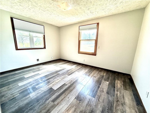 spare room featuring baseboards, a textured ceiling, plenty of natural light, and wood finished floors