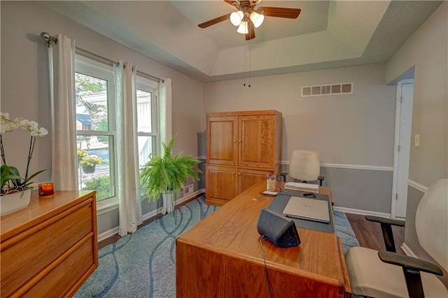 office area featuring a ceiling fan, baseboards, visible vents, a raised ceiling, and dark wood-style floors