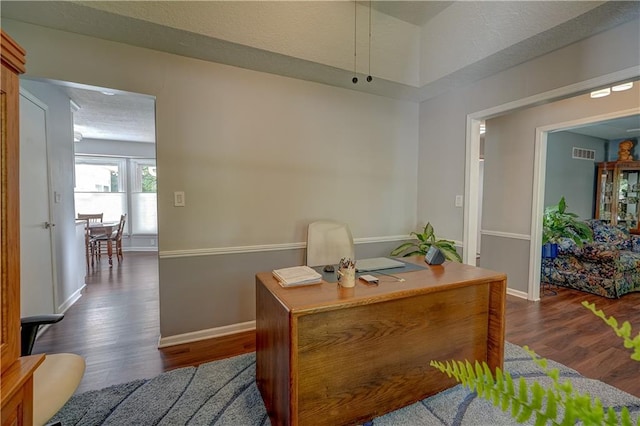 office space with dark wood finished floors, visible vents, and baseboards