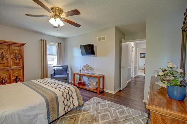 bedroom with a textured ceiling, baseboards, dark wood-type flooring, and visible vents