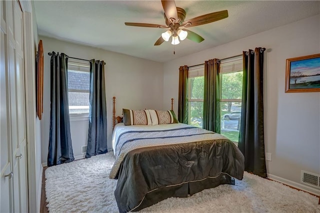carpeted bedroom with baseboards, visible vents, and a ceiling fan
