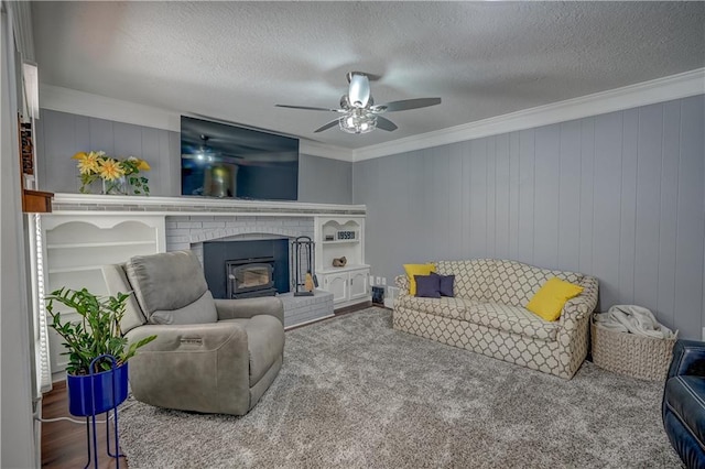 carpeted living room featuring ceiling fan, ornamental molding, a textured ceiling, and a brick fireplace