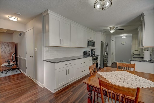 kitchen featuring stainless steel appliances, a textured ceiling, decorative backsplash, dark wood-style floors, and a ceiling fan