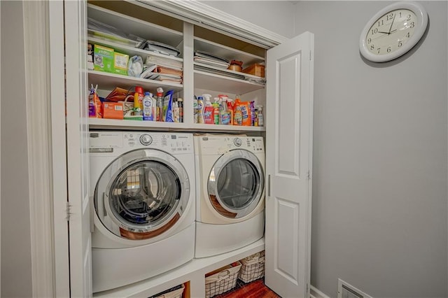 clothes washing area featuring washing machine and clothes dryer, wood finished floors, and laundry area
