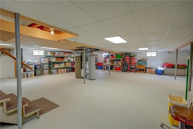 basement featuring heating unit, a wealth of natural light, gas water heater, and a paneled ceiling
