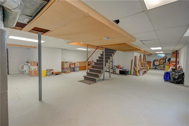 below grade area featuring a paneled ceiling and stairs