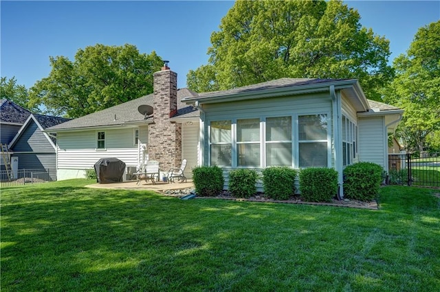rear view of property with a yard, fence, a patio, and a chimney
