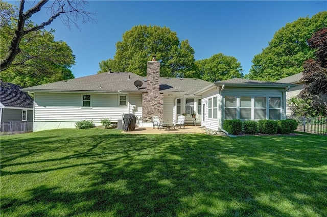 rear view of house featuring a chimney, a yard, a patio, and fence