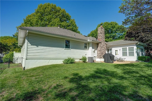 back of property with a chimney, a patio, fence, and a lawn