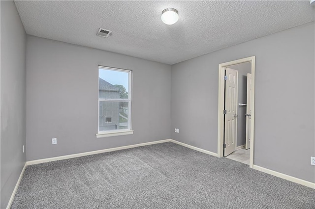 empty room featuring carpet, a textured ceiling, and baseboards