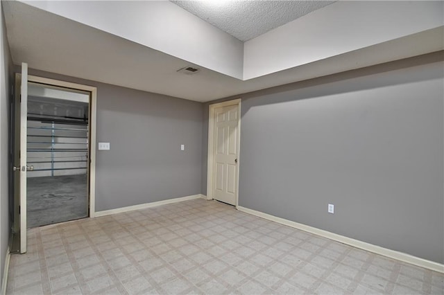 empty room featuring baseboards, a textured ceiling, and light floors