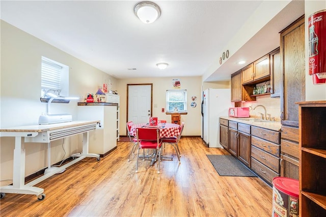 kitchen featuring freestanding refrigerator, plenty of natural light, light wood finished floors, and a sink