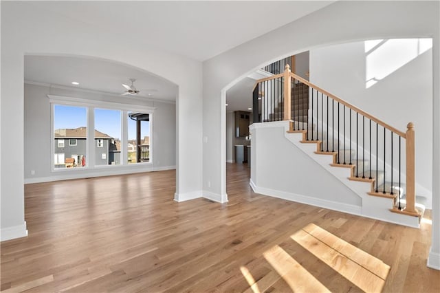 25256 W 149th Ter, Olathe, KS 66061 - unfurnished living room with wood finished floors, baseboards, ceiling fan, arched walkways, and stairs