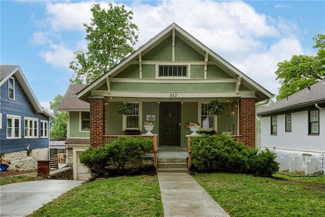 bungalow-style home with a porch, a front yard, driveway, and an attached garage
