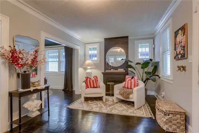 sitting room featuring baseboards, a textured ceiling, crown molding, and wood finished floors