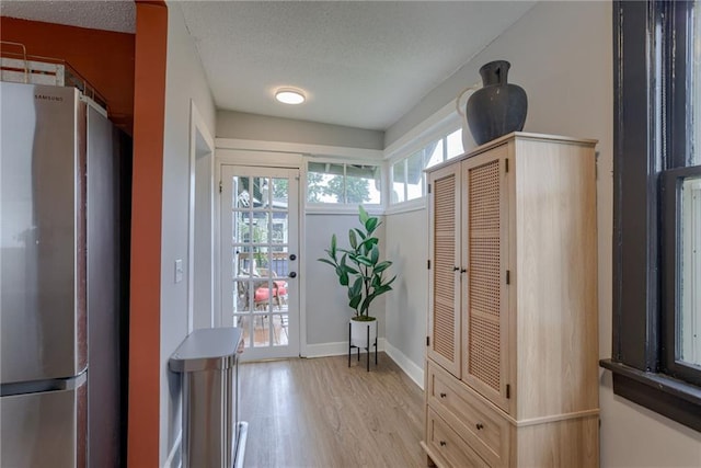 mudroom with light wood-style flooring, a textured ceiling, and baseboards