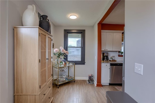 kitchen with dishwasher, light wood finished floors, baseboards, tasteful backsplash, and white cabinetry
