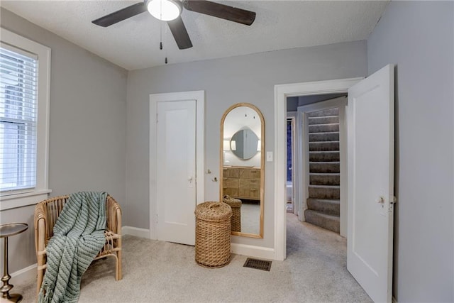 sitting room featuring carpet, plenty of natural light, ceiling fan, baseboards, and a textured ceiling