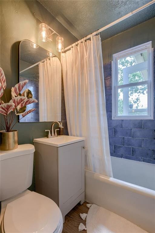 full bath with toilet, a textured ceiling, shower / bath combo, vanity, and wood finished floors