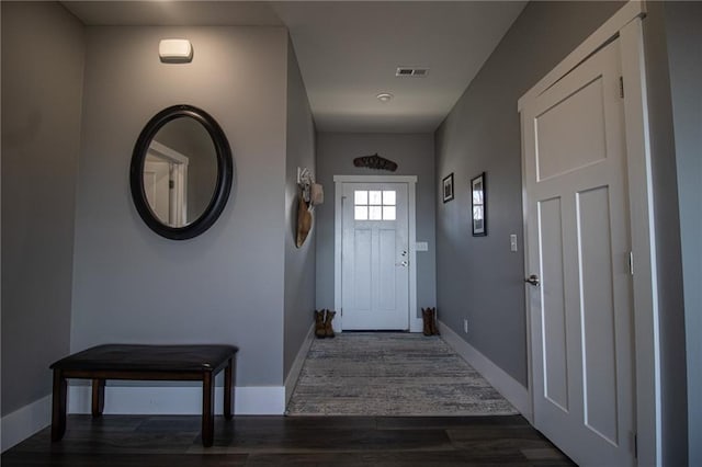 doorway to outside with baseboards, visible vents, and dark wood-type flooring