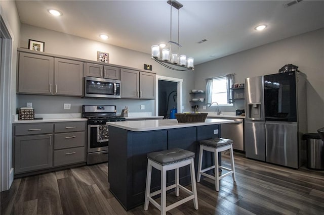 kitchen featuring a breakfast bar, light countertops, appliances with stainless steel finishes, and gray cabinetry