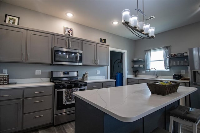 kitchen featuring a sink, open shelves, gray cabinets, appliances with stainless steel finishes, and dark wood-style floors