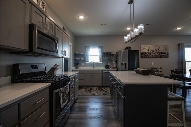 kitchen featuring a kitchen bar, a sink, open shelves, stainless steel appliances, and visible vents